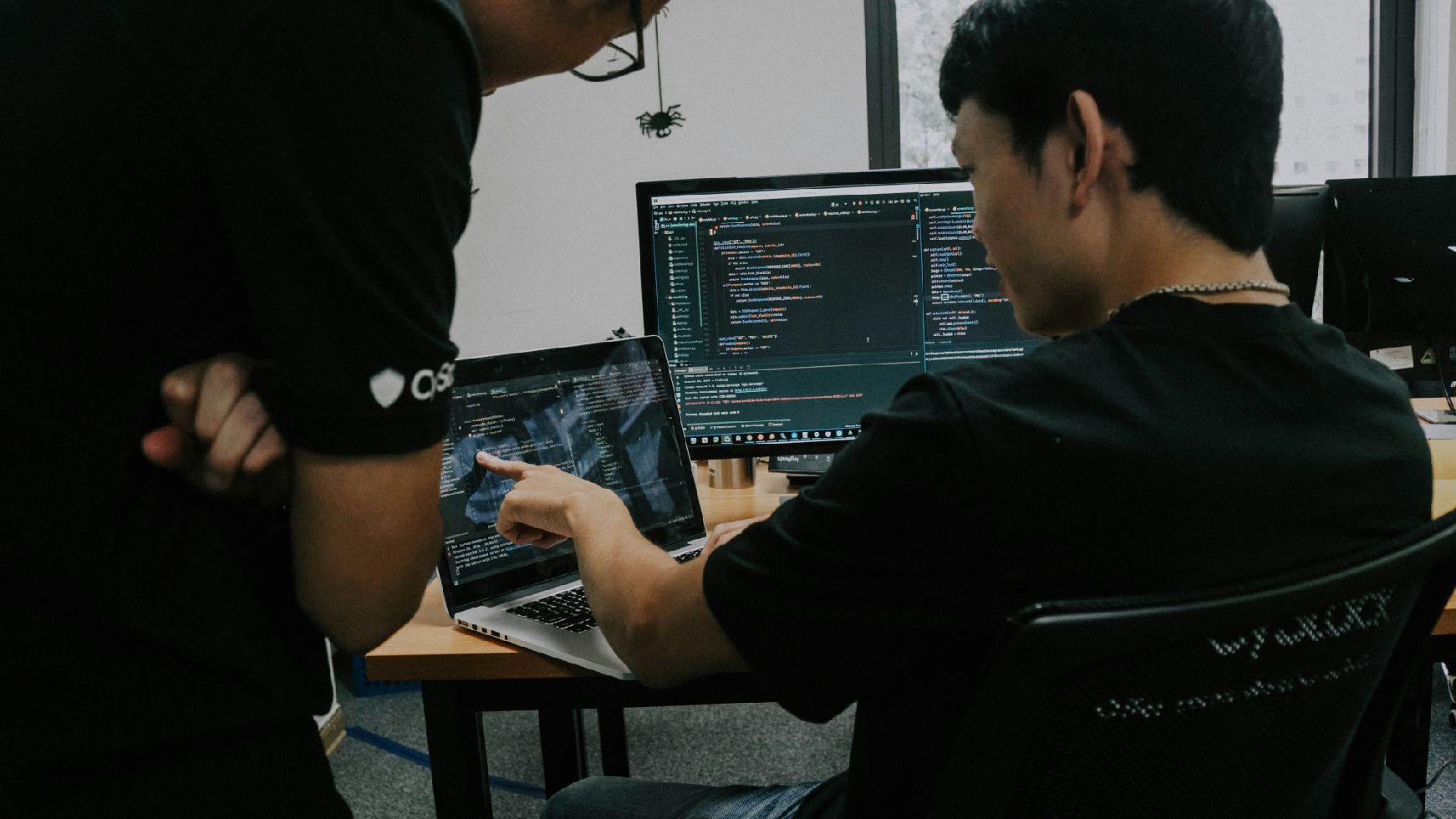 Personen vor Bildschirmen mit Code am Bildschirm