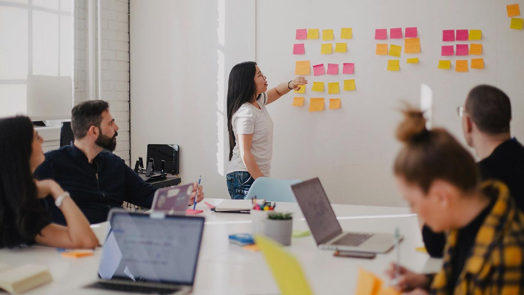 Frau steht vor einem Whiteboard und unterrichtet eine Gruppe von Personen