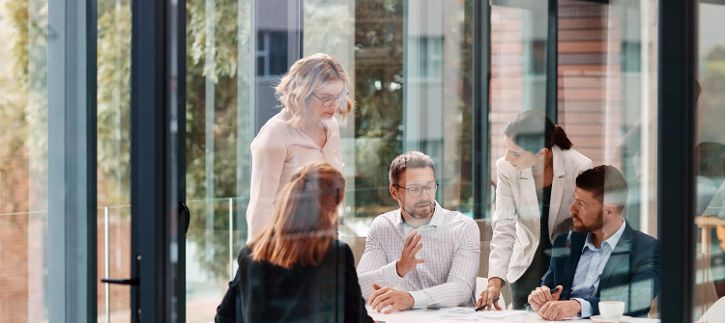 Menschen hinter einem Fenster mit Spiegelung in Arbeitsumgebung &copy; ReeseArcus/peopleimages.com  - AdobeStock 