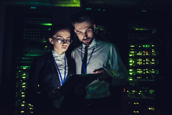 Frau und Mann mit Tablet in der Hand stehen in einem Serverraum © Vasyl - AdobeStock