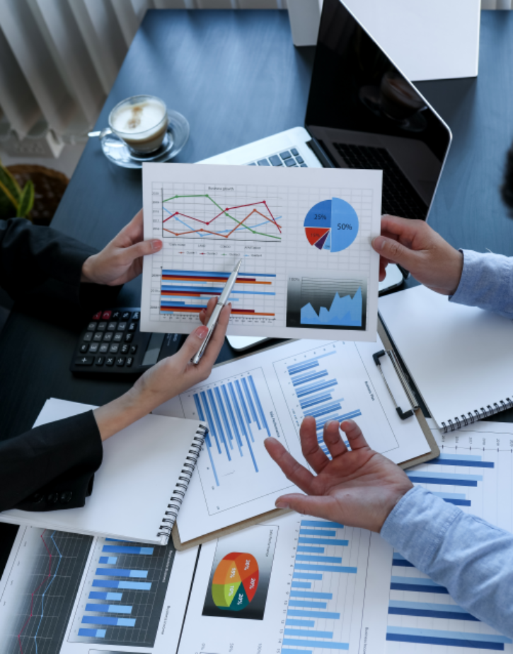 Zwei Personen sitzen am Tisch und diskutieren über Tabellen und Grafiken © David - AdobeStock