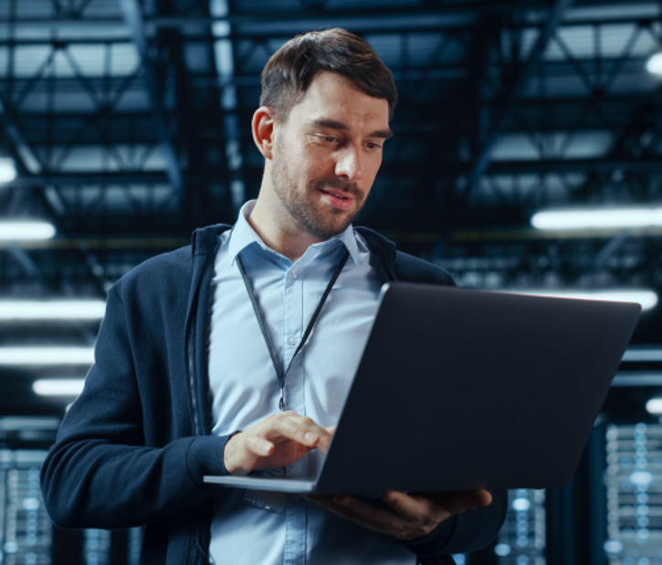 Mann steht mit Laptop in einem Serverraum © Gorodenkoff - AdobeStock