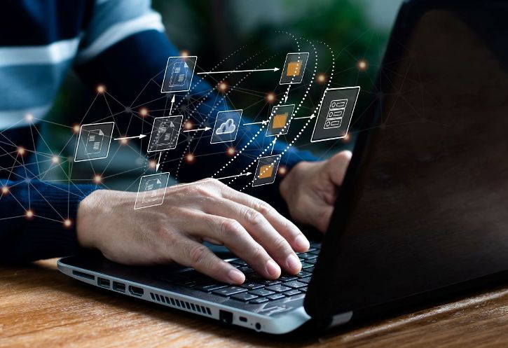 Mann sitzt vor Laptop. Im Vordergrund sieht man ein Hologramm mit Icons © U-STUDIOGRAPHY DD59  - AdobeStock 509184195 