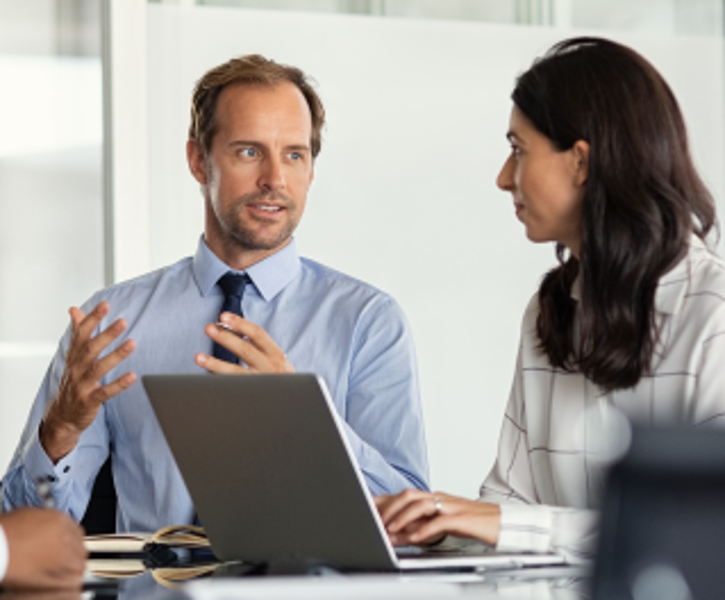 Drei Männer und eine Frau sitzen bei einem Meeting mit Laptops und diskutieren miteinander © Rido - AdobeStock