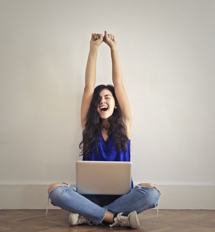 Frau sitzt im Schneidersitz am Boden mit einem Laptop auf ihrer Beinen. &copy; Andrea Piacquadio  - pexels 