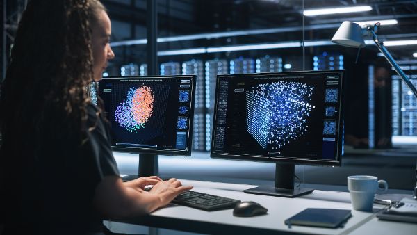 Frau vor Bildschirmen in einem Serverkontrollraum