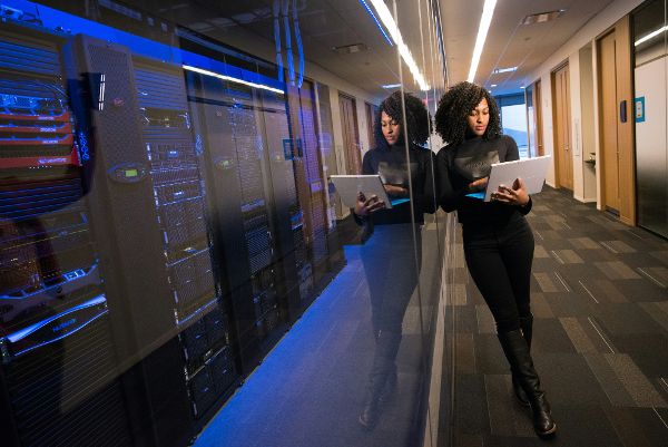 Frau mit Laptop vor einem Serverraum