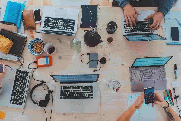 Tisch mit diversen Laptops und elektronischen Geräten © Marvin Meyer   - Unsplash 