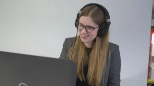 Frau mit Headset vor Computerbildschirm