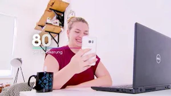 Frau sitzt mit Smartphone vor Laptop