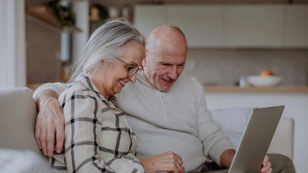 Ein Mann und eine Frau sitzen lachend vor einem Laptop ©  Unsplash+ 