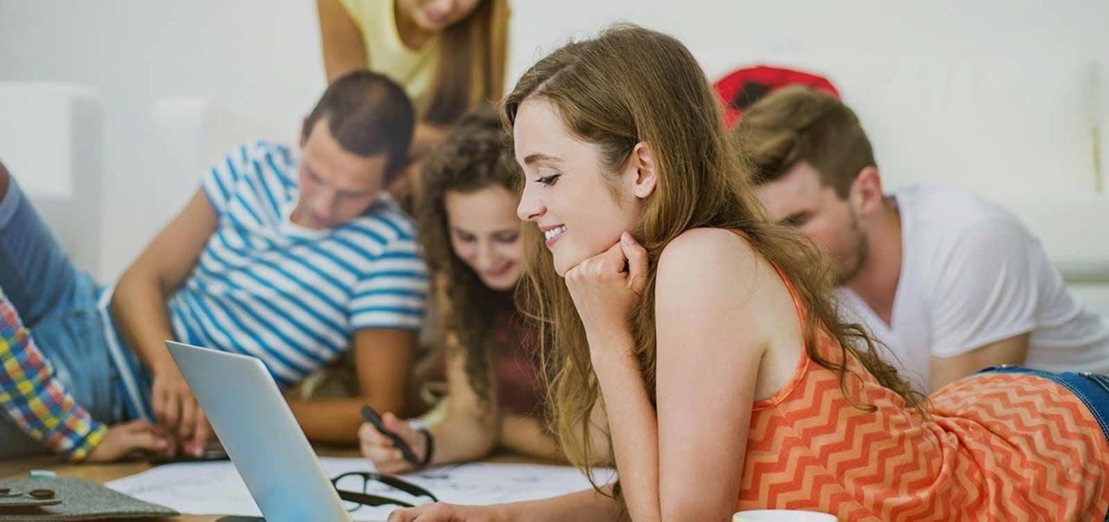 Gruppe von Personen liegt auf dem Boden und arbeitet gemeinsam mit Laptops und Schreibzeug an einem Projekt © Unsplash+