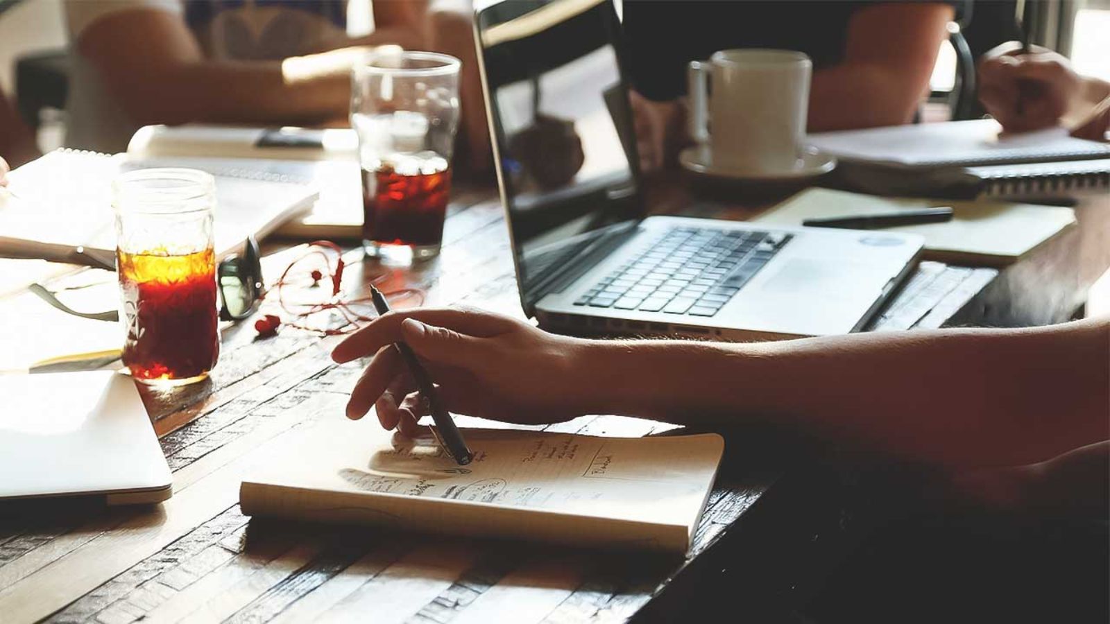 Vollgeräumter Tisch mit Laptop und Hand mit Stift © StartupStockPhotos - pixabay.com