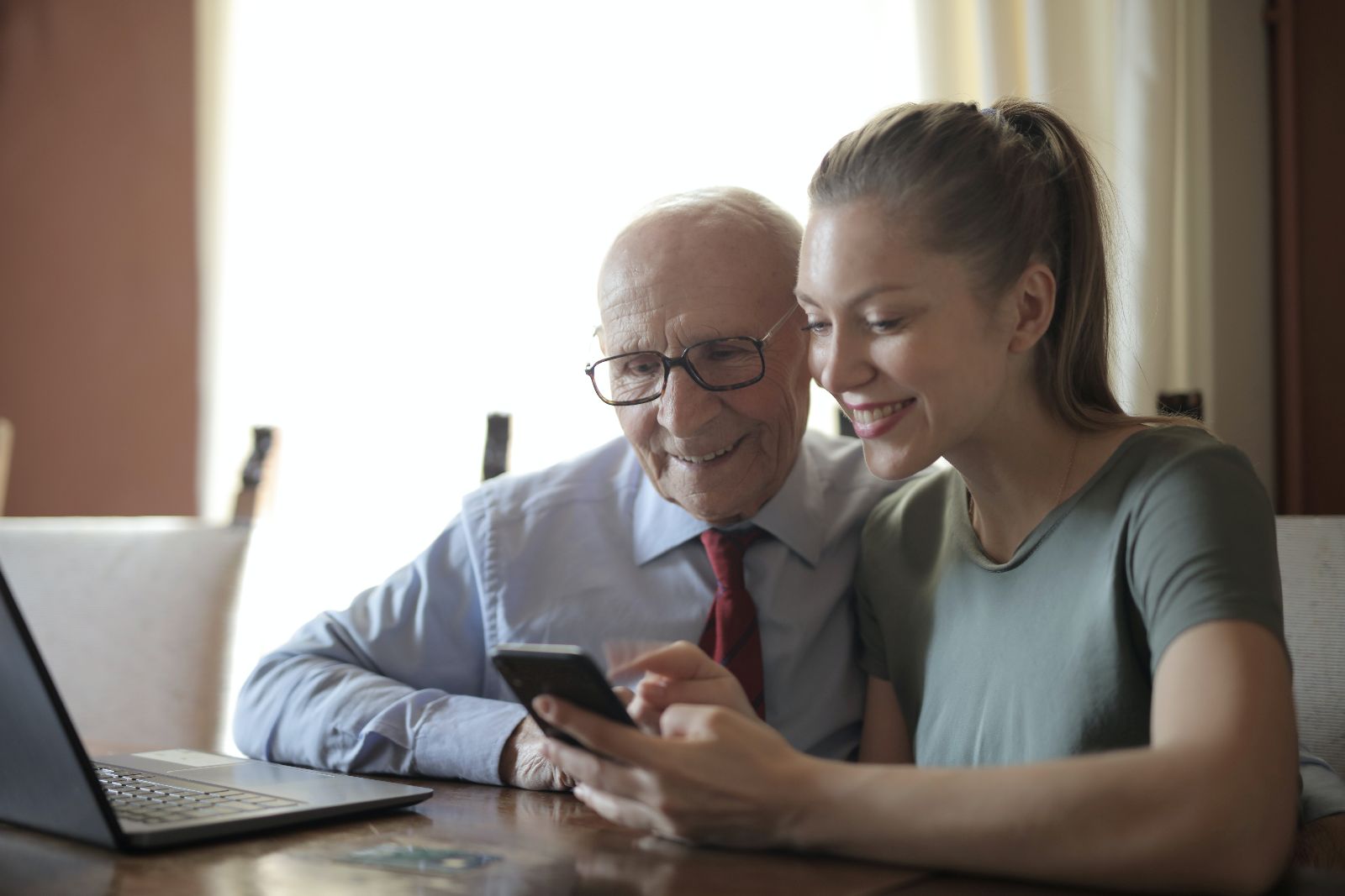 Junge Frau erklärt älterem Mann etwas auf dem Smartphone. &copy; Andrea Piacquadio  - pexels 