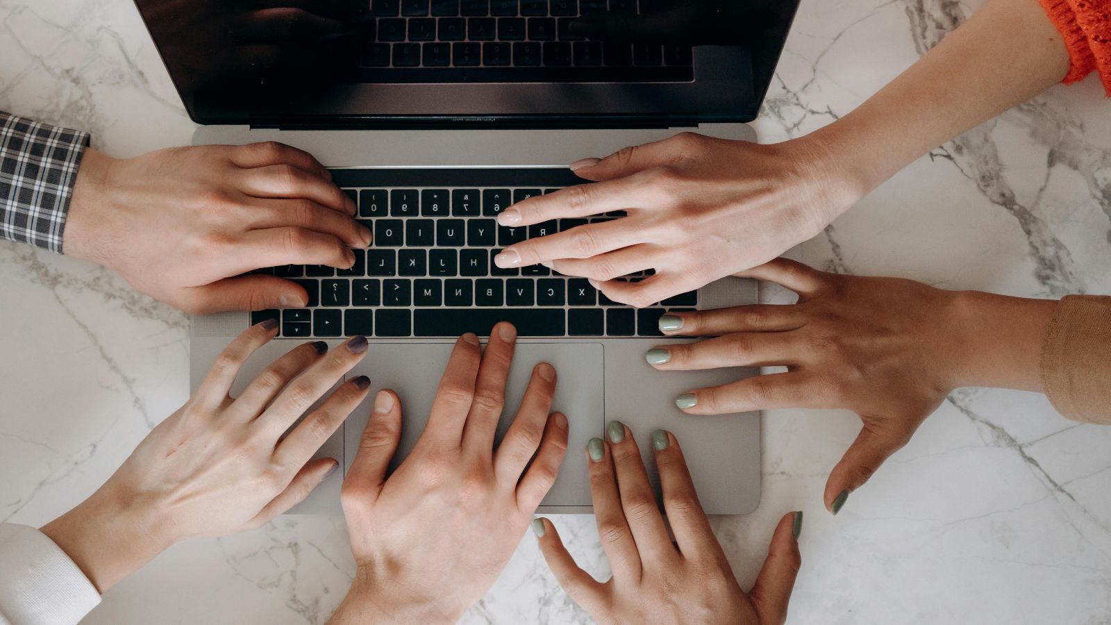 Sechs Hände auf Laptop © Mikhail Nilov - pexels