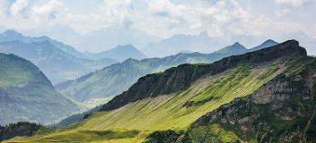 Ein malerischer Blick auf eine Bergkette mit grünen Bergen im Hintergrund © Jacek Dylag  - Unsplash 