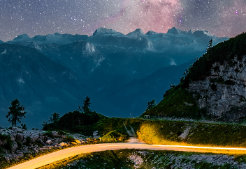 Straße am Berg mit Lichtstahl unter einem Sternenhimmel © Samir  - AdobeStock 