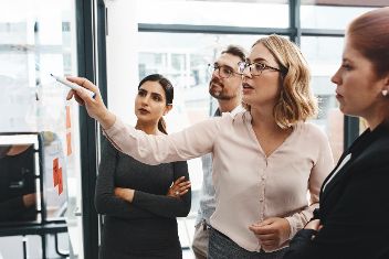 Gruppe an Personen vor einer Tafel mit Notizen stehend. &copy;  Adobe Stock 