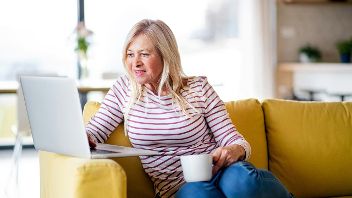 Ältere Frau sitzt mit Kaffeetasse vor Laptop ©  Unsplash+ 