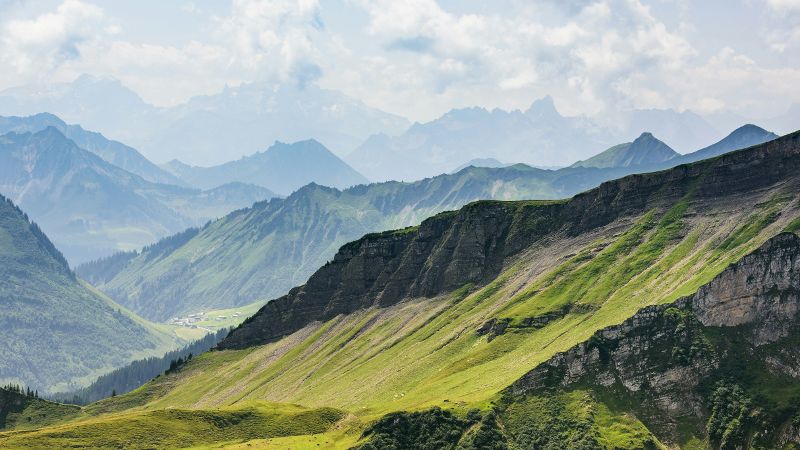 Ein malerischer Blick auf eine Bergkette mit grünen Bergen im Hintergrund © Jacek Dylag  - Unsplash 