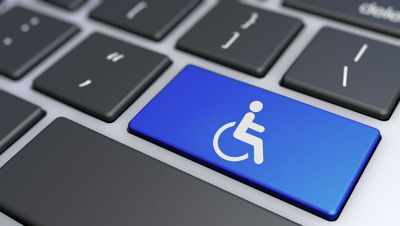Eine blaue Computer-Tastatur-Taste mit einem Rollstuhl-Symbol darauf signalisiert Barrierefreiheit im Internet.