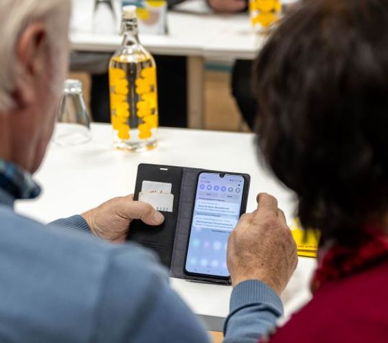 zwei ältere Menschen bedienen ein Smartphone