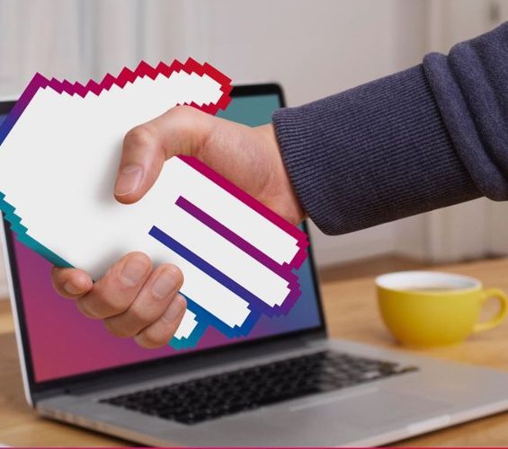 man shaking hands in front of a laptop