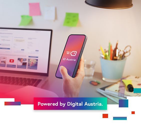 Hintergrund ist ein Laptopbildschirm angeschnitten von Home FinanzOnline. Mobilphone mit Schlüssellogo der ID Austria. darunter ein Balken in bunten Farben mit dem Schriftzug Powered by Digital Austria